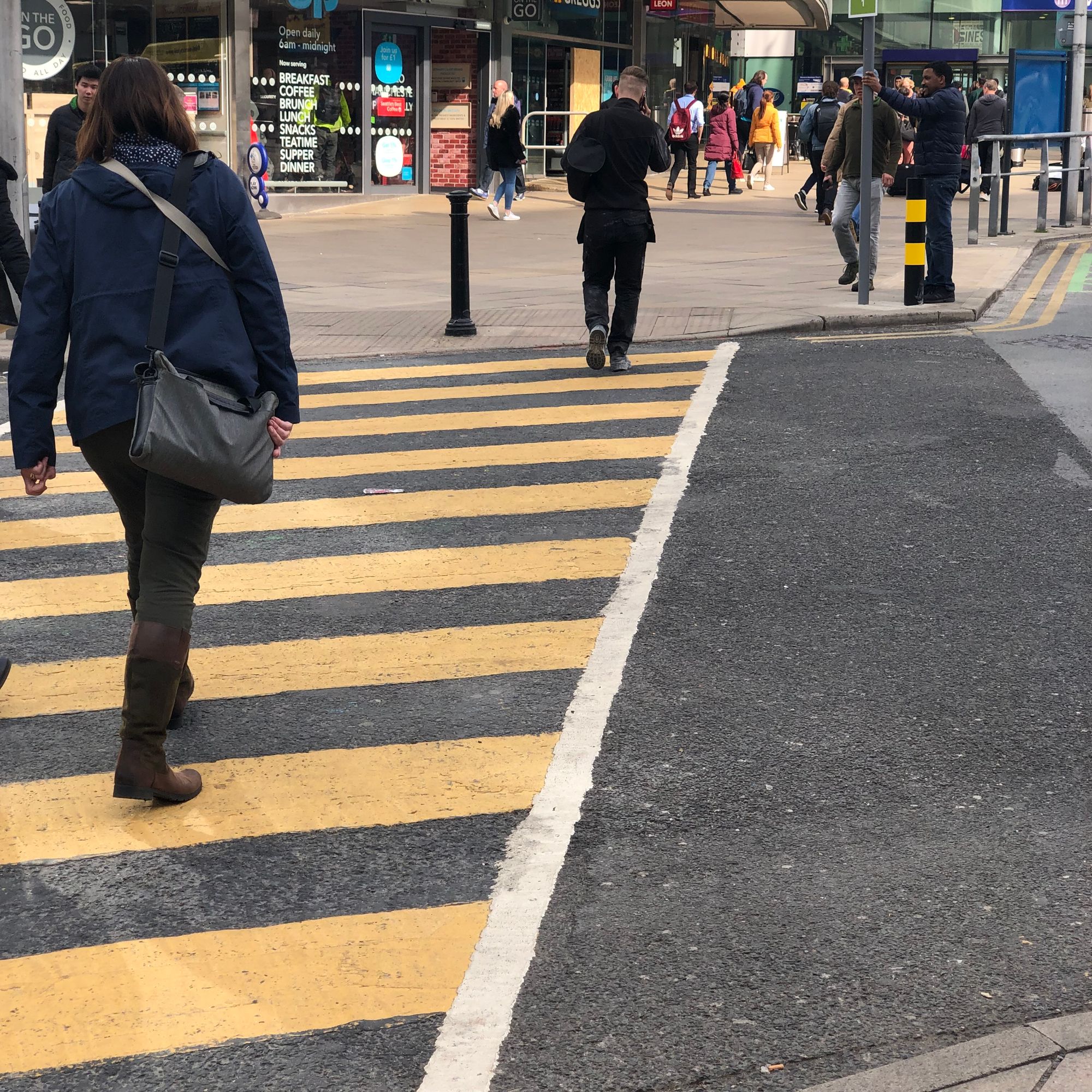 A road crossing marked with oblong tactile paving and black and yellow stripes.