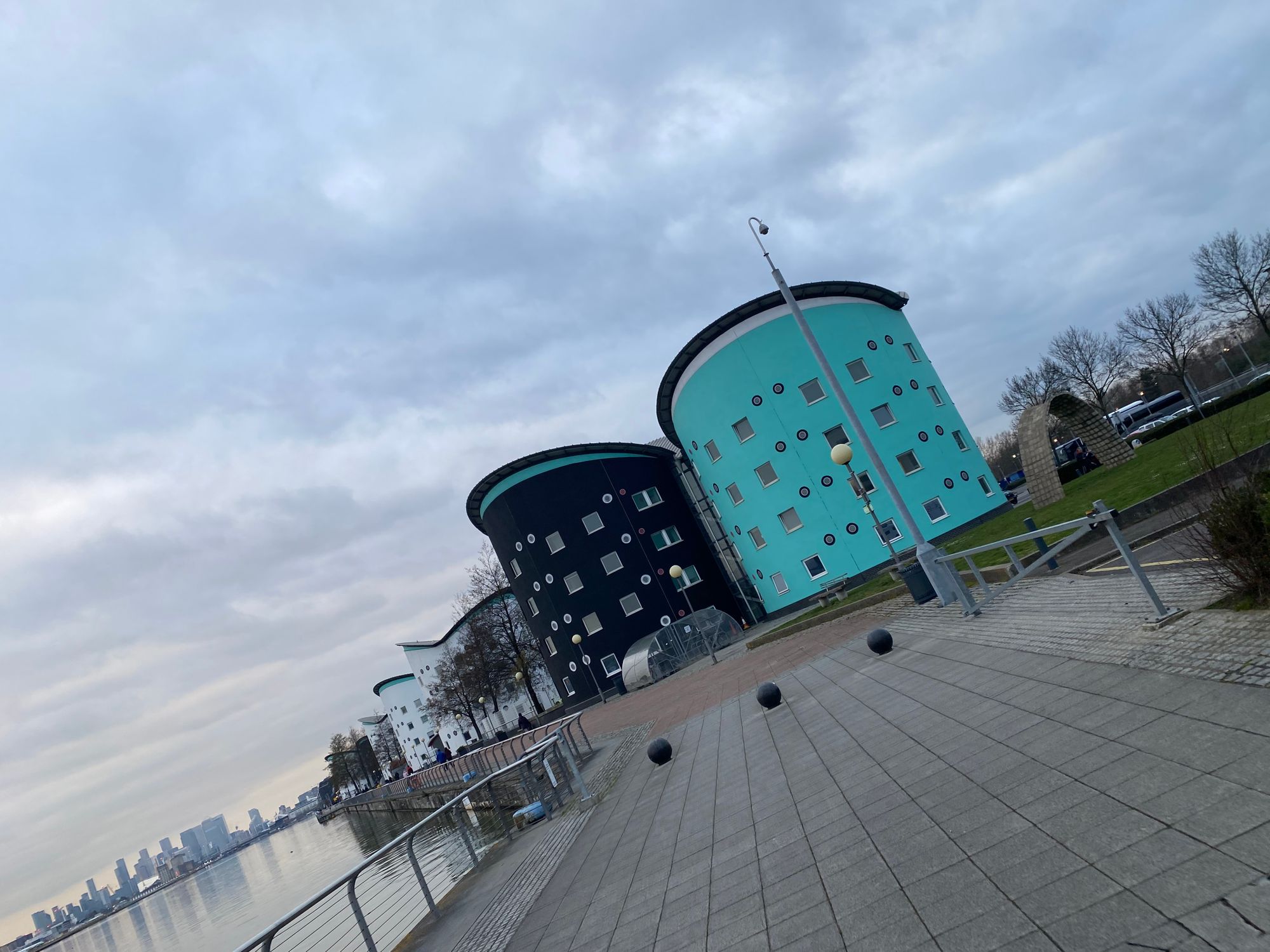 Cylindrical residential buildings with colourful walls on a dockside with the London skyline in the background