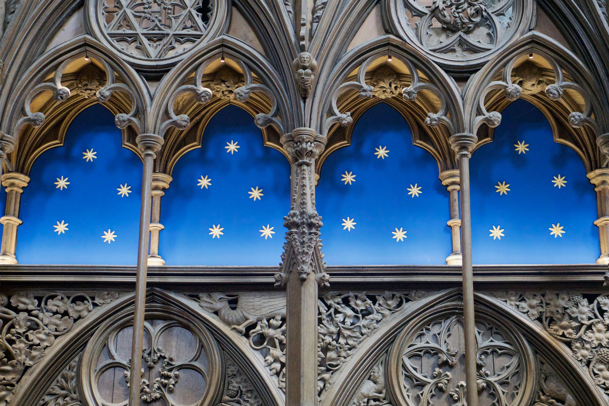Arches in the cathedral wall with a blue backdrop with five gilded stars in each segment.
