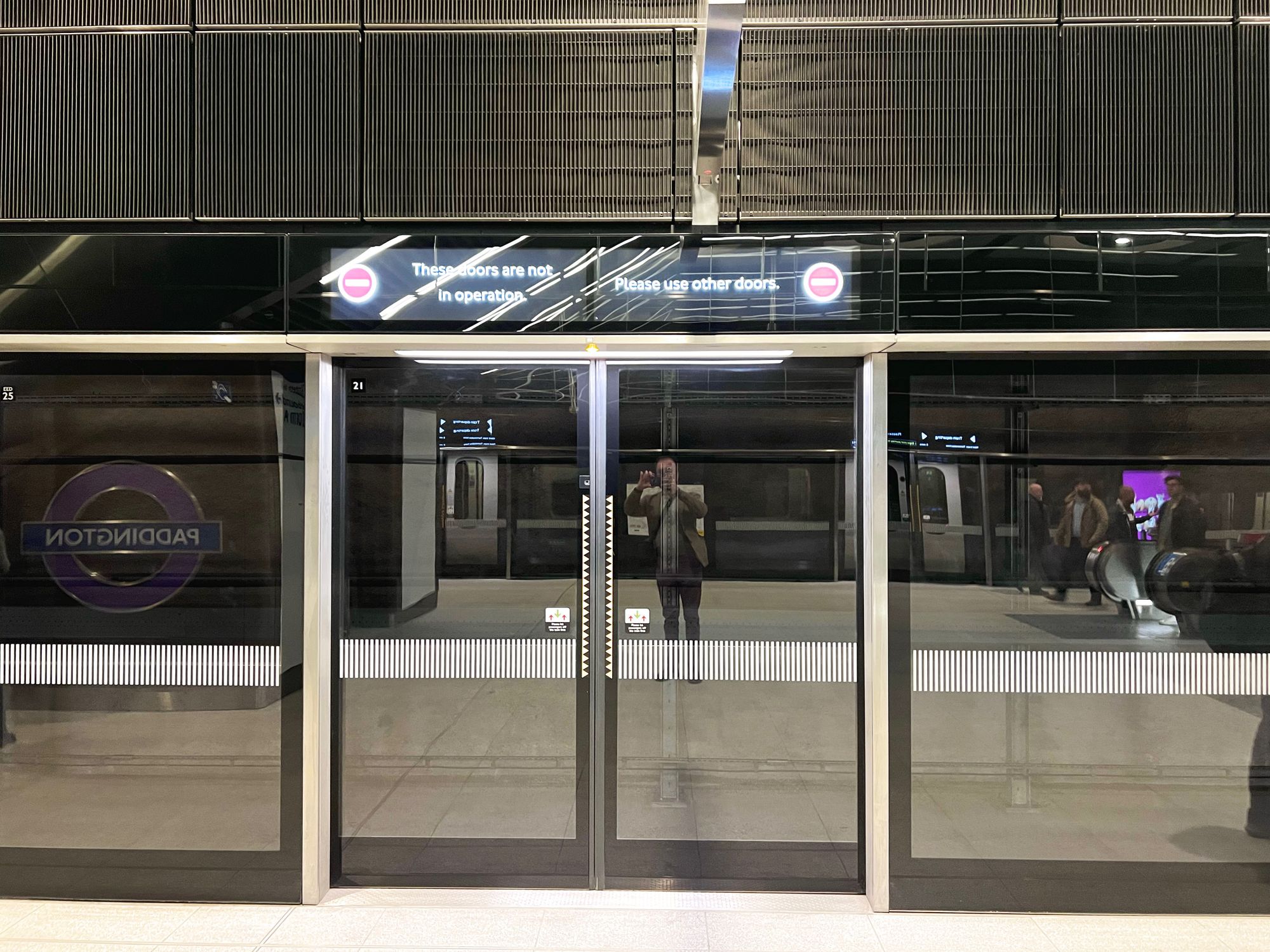 A set of platform screen doors. The departures screen above the doors says: "These doors are not in operation. Please use other doors."