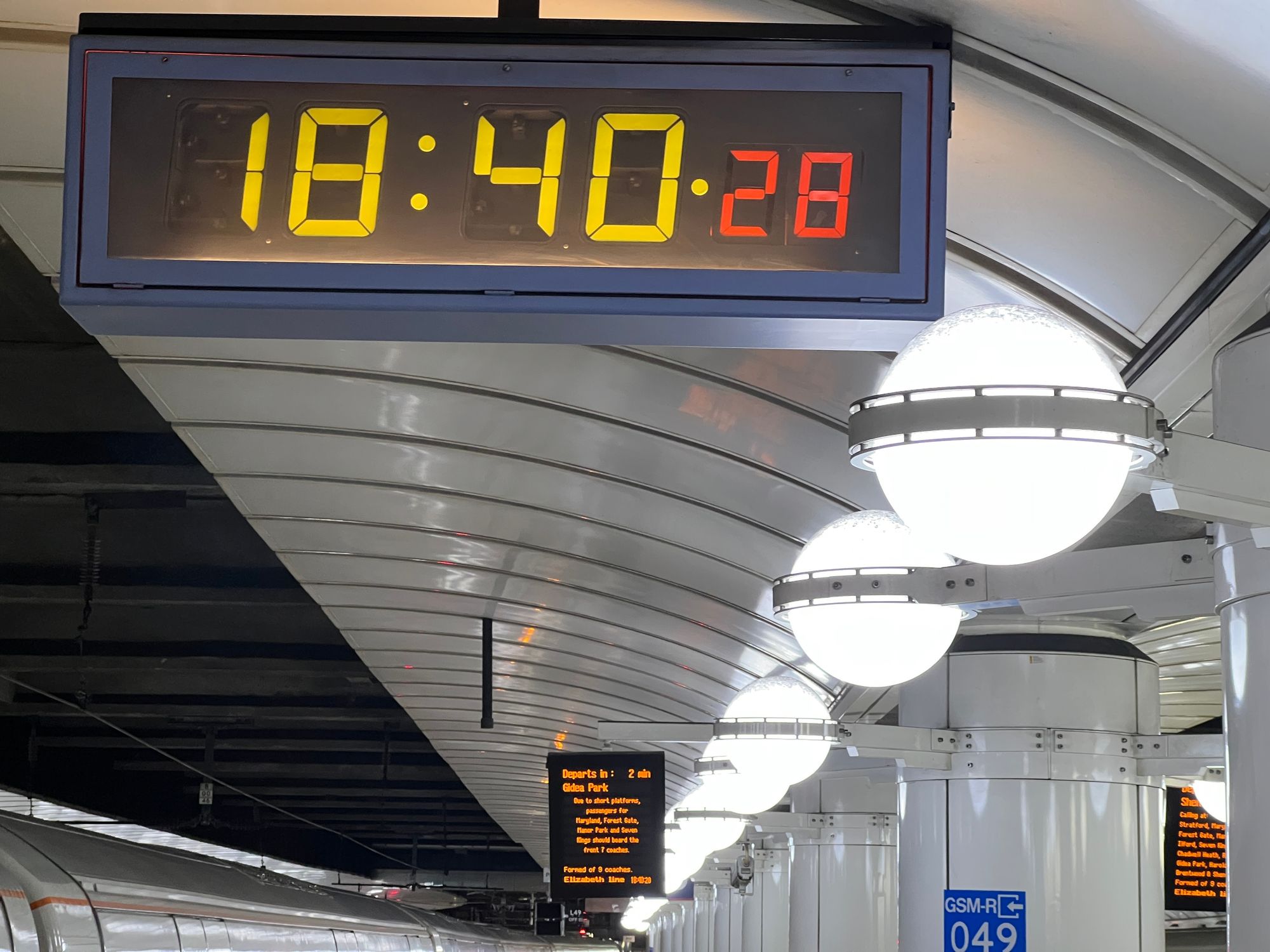 A mechanical seven-segment display clock on a station platform at Liverpool Street reads 18:40:28.