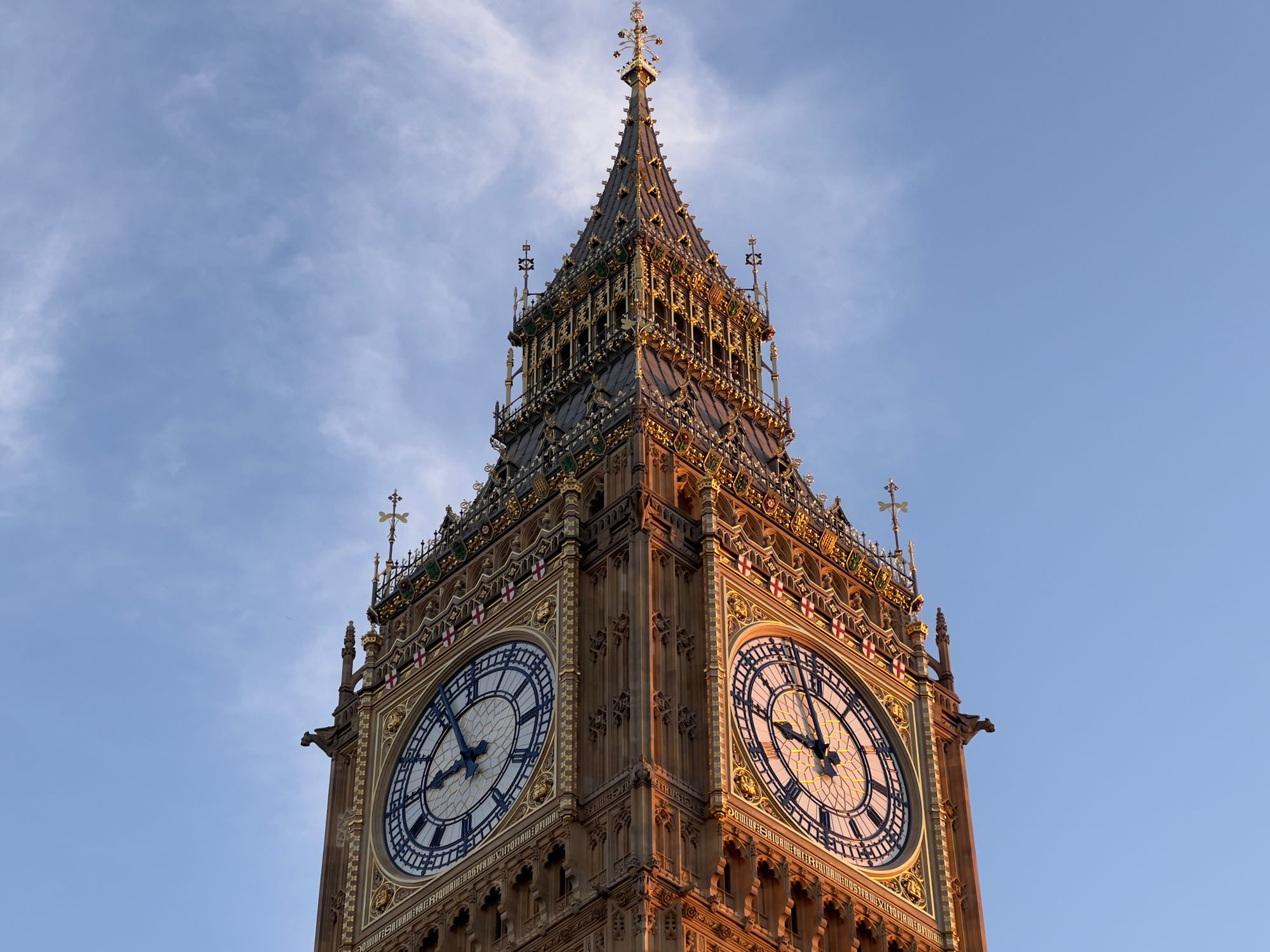 The clock tower of the Houses of Parliament in London, in the golden light, taken from a corner.