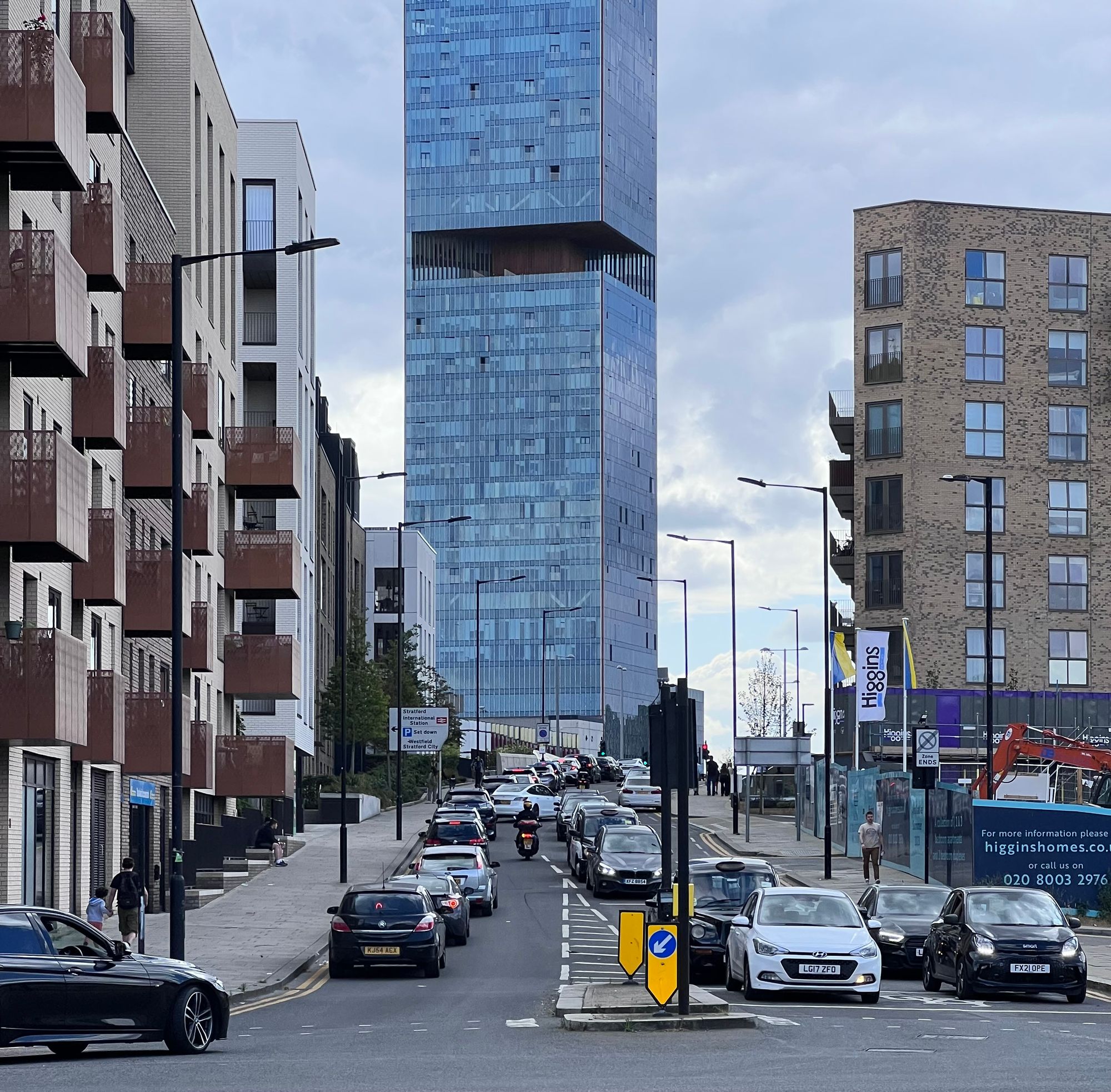 Queues of traffic towards and away from a tall glass building.