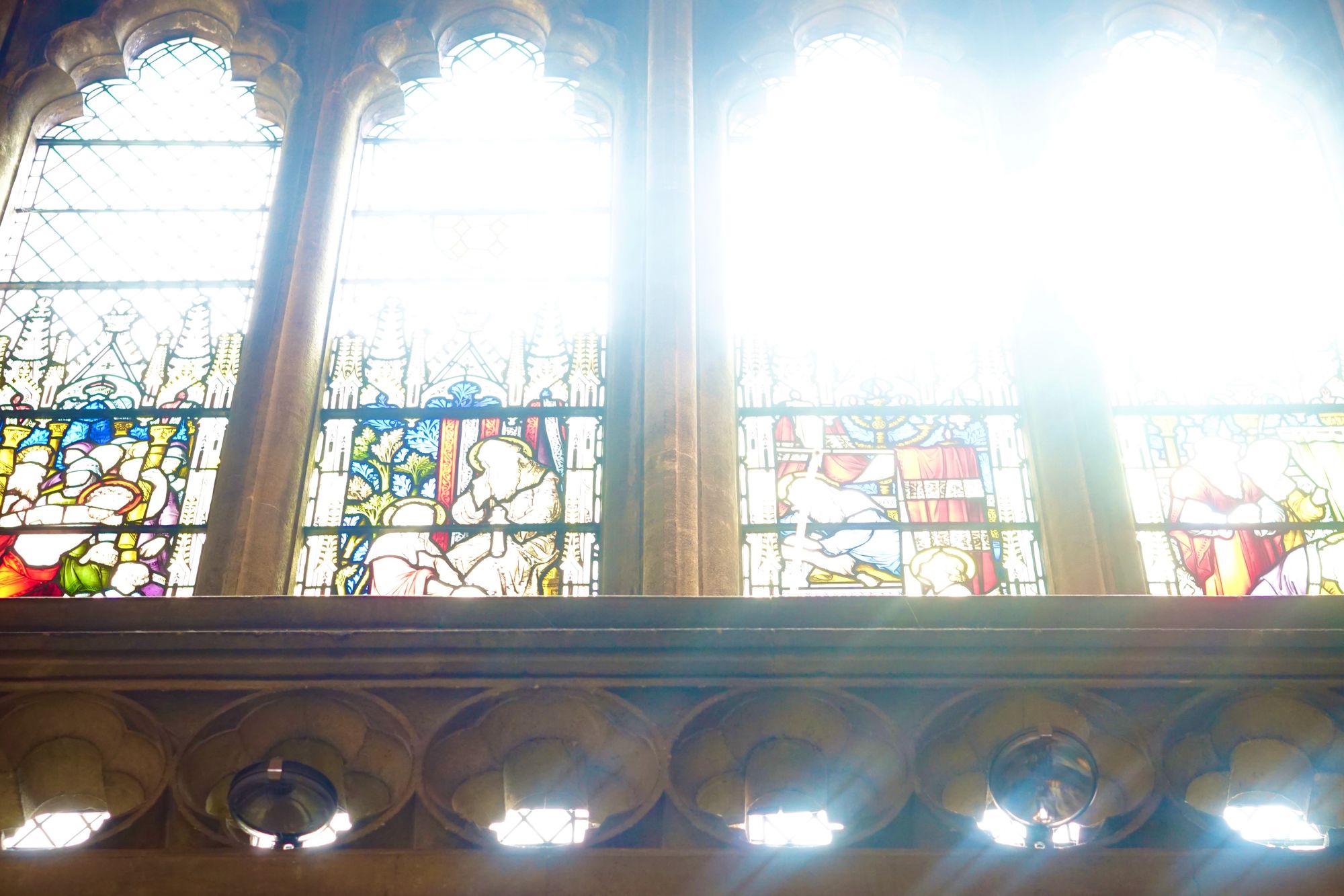 Bright light behind a row of stained glass windows.