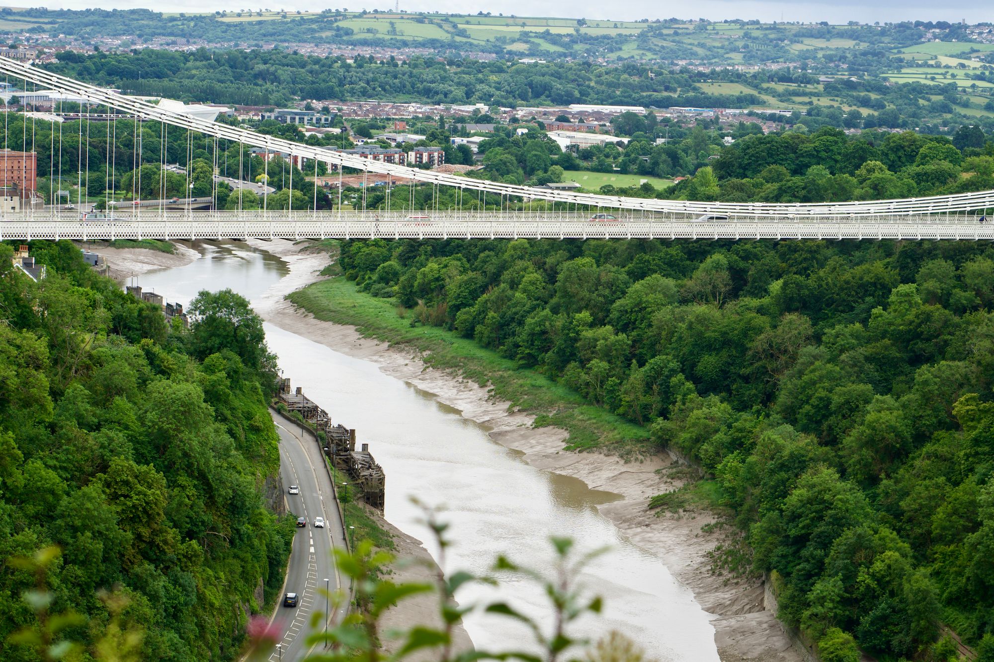 Close-up of suspension bridge road deck with cars passing along it.