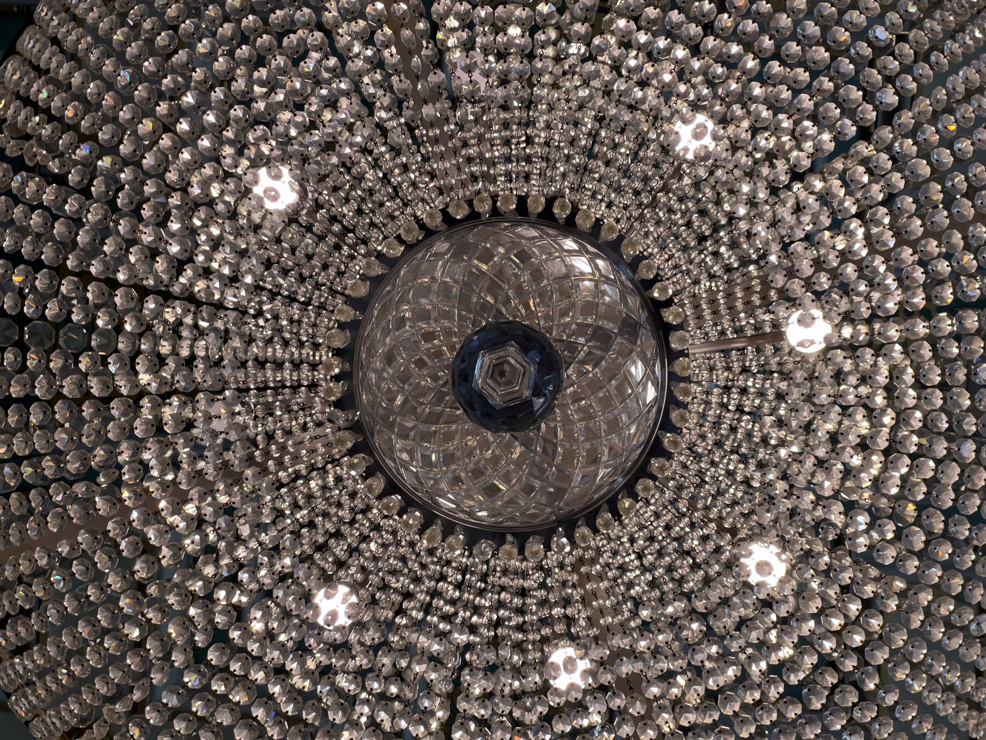 An ornate chandelier photographed from below with a big glass sphere in the centre and lots of little ones radiating out.
