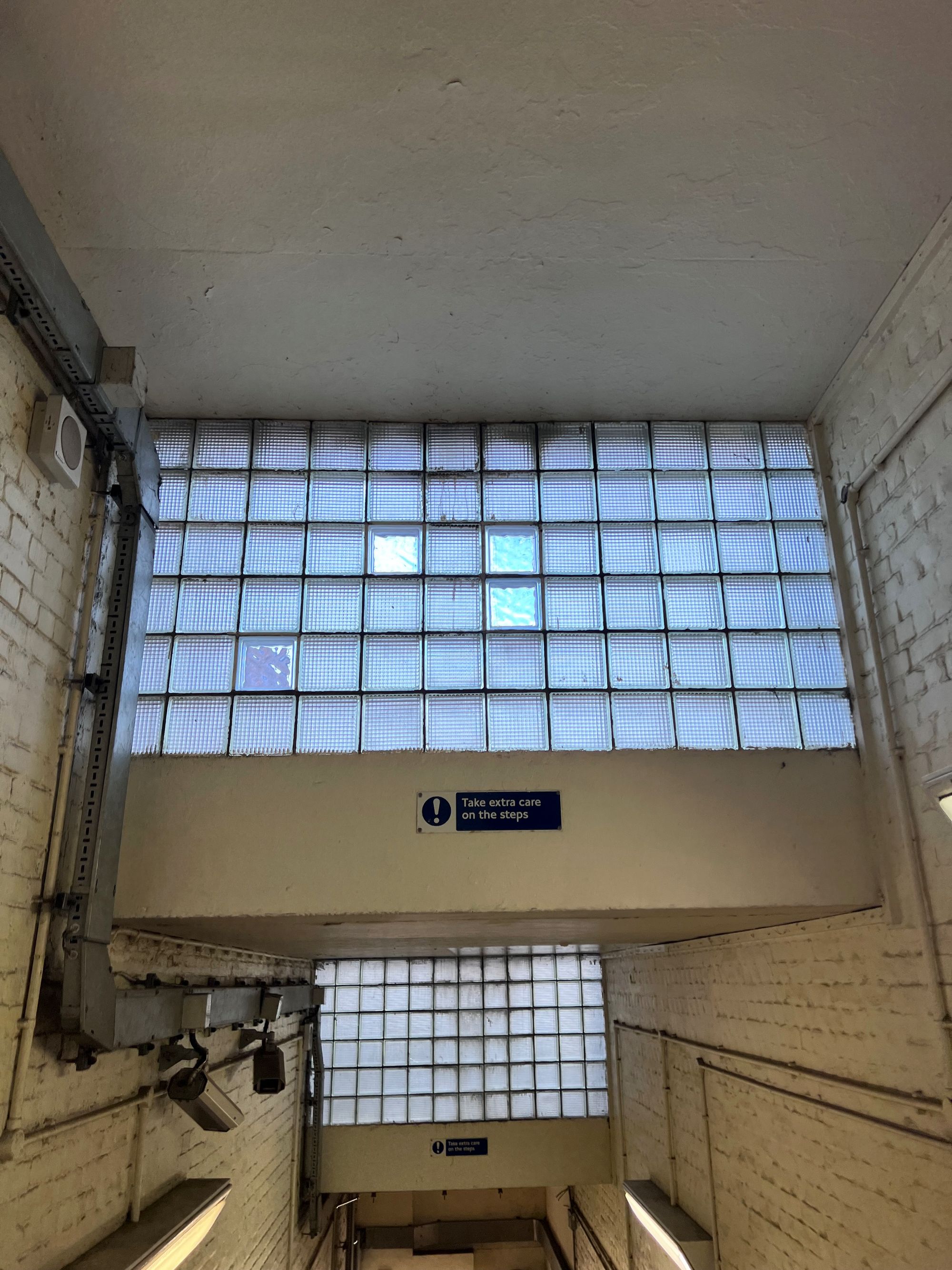 The brick ceiling of a staircase with skylights made up of glass squares.