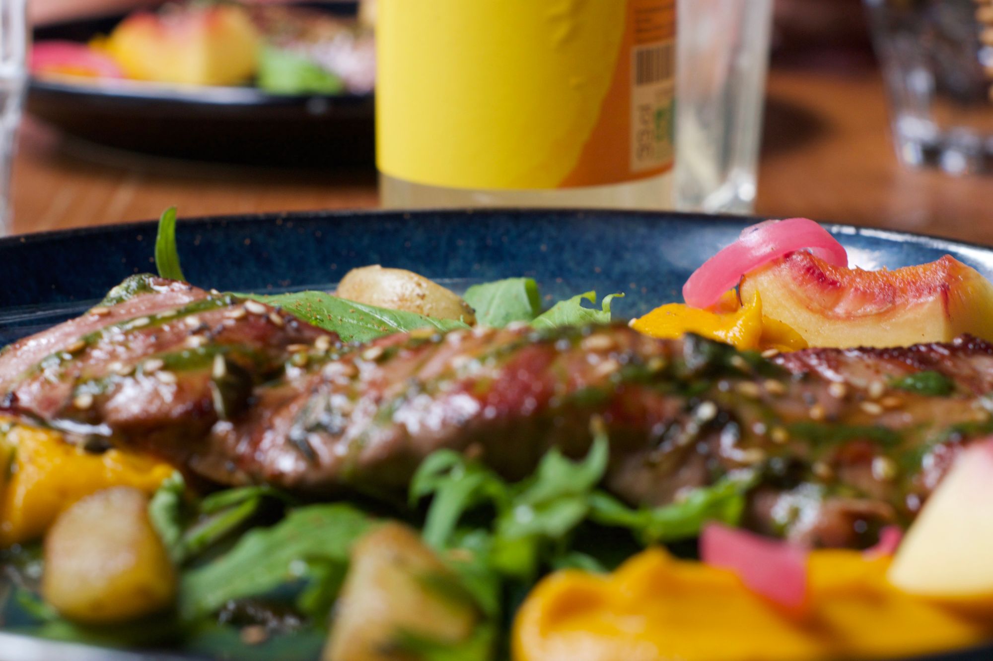 A colourful salad of chargrilled veal with potatoes, nectarines, and greens, in close up.