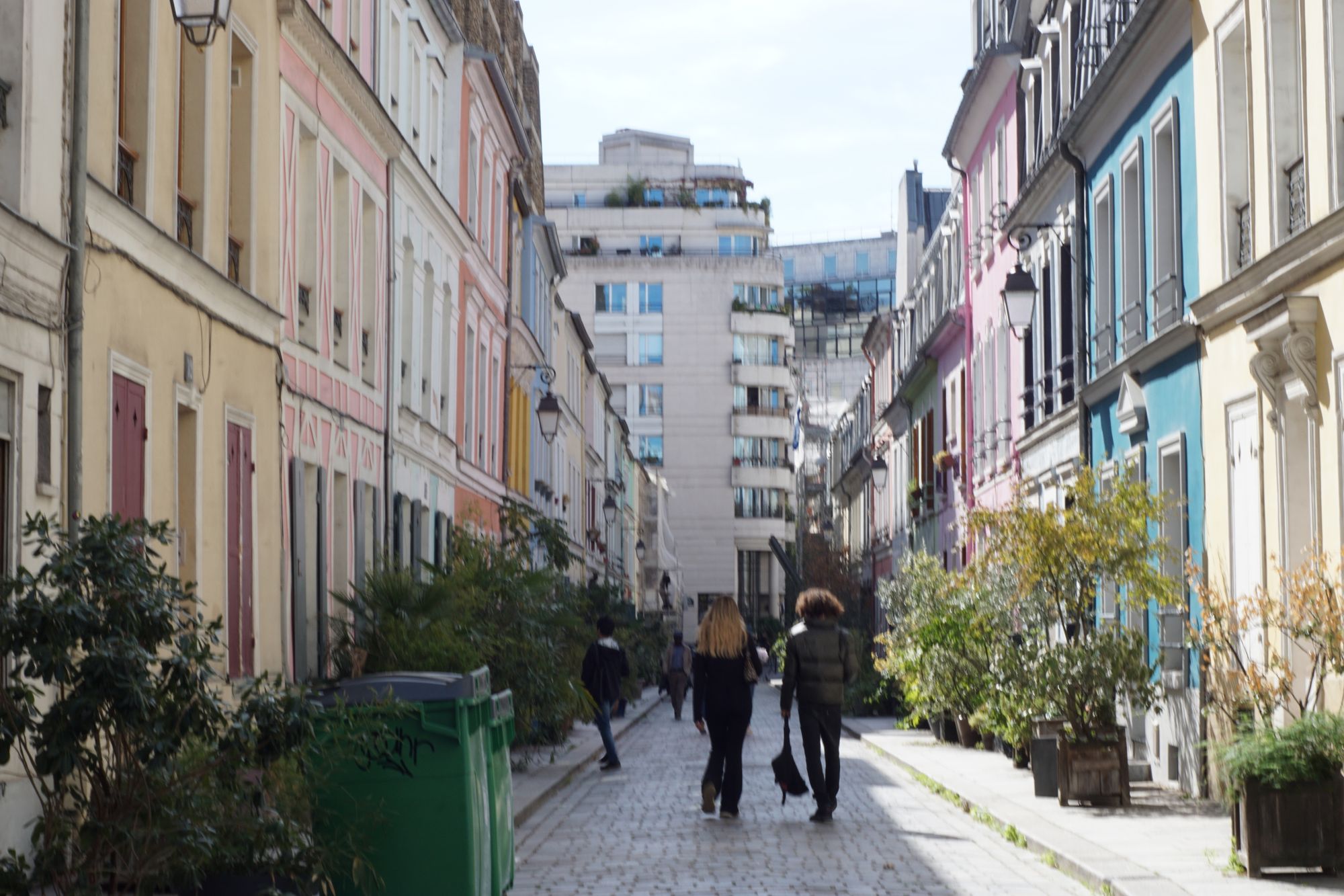 A pedestrianised street with pastel-coloured houses on both sides people walking down it. The photo is ever so slightly out of focus and there's also some blur coming from camera strake that's just distracting enough to be noticeable.