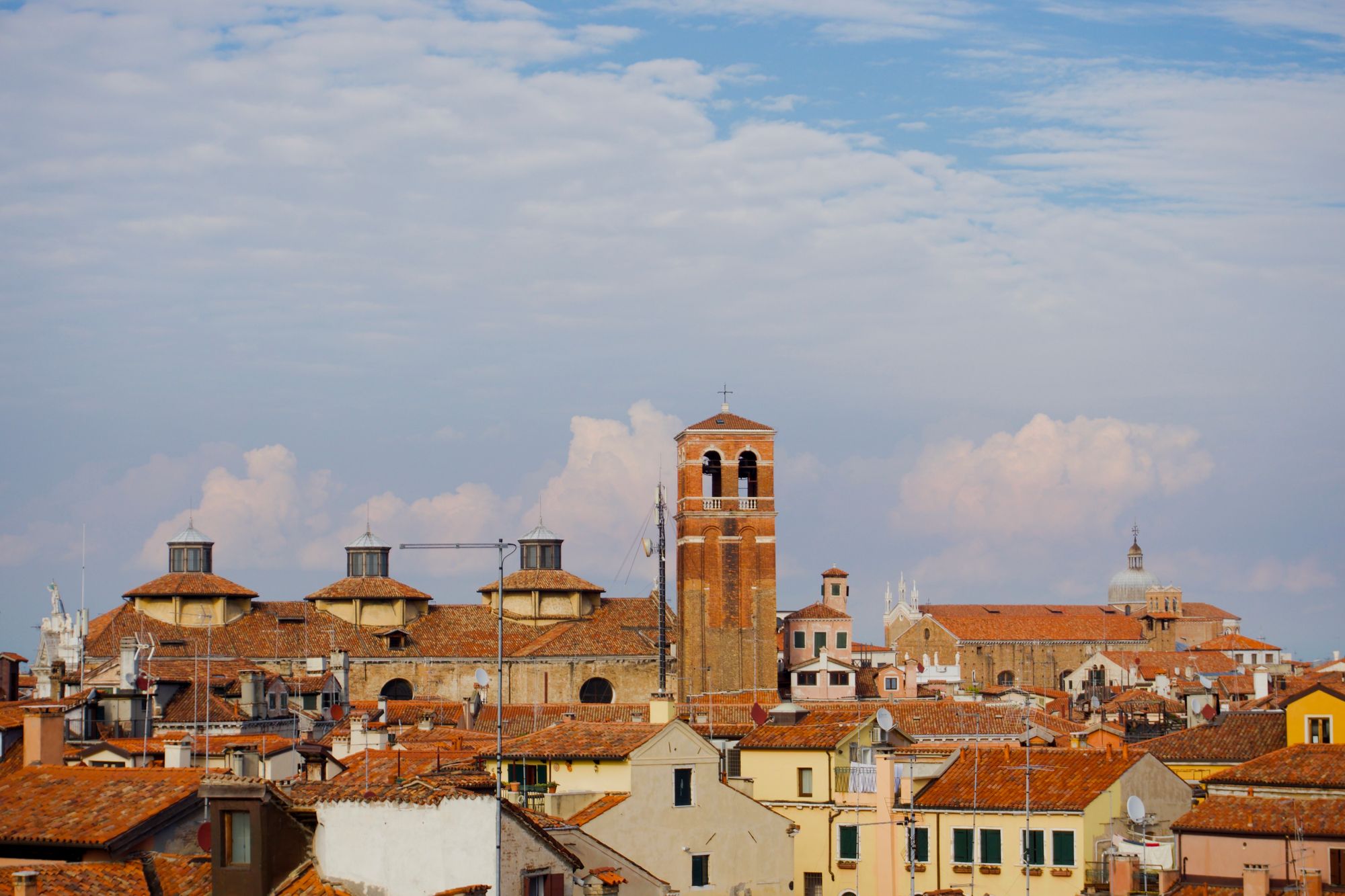 Terracotta-coloured roofs in the foreground with towering cumulus clouds rising in the background.