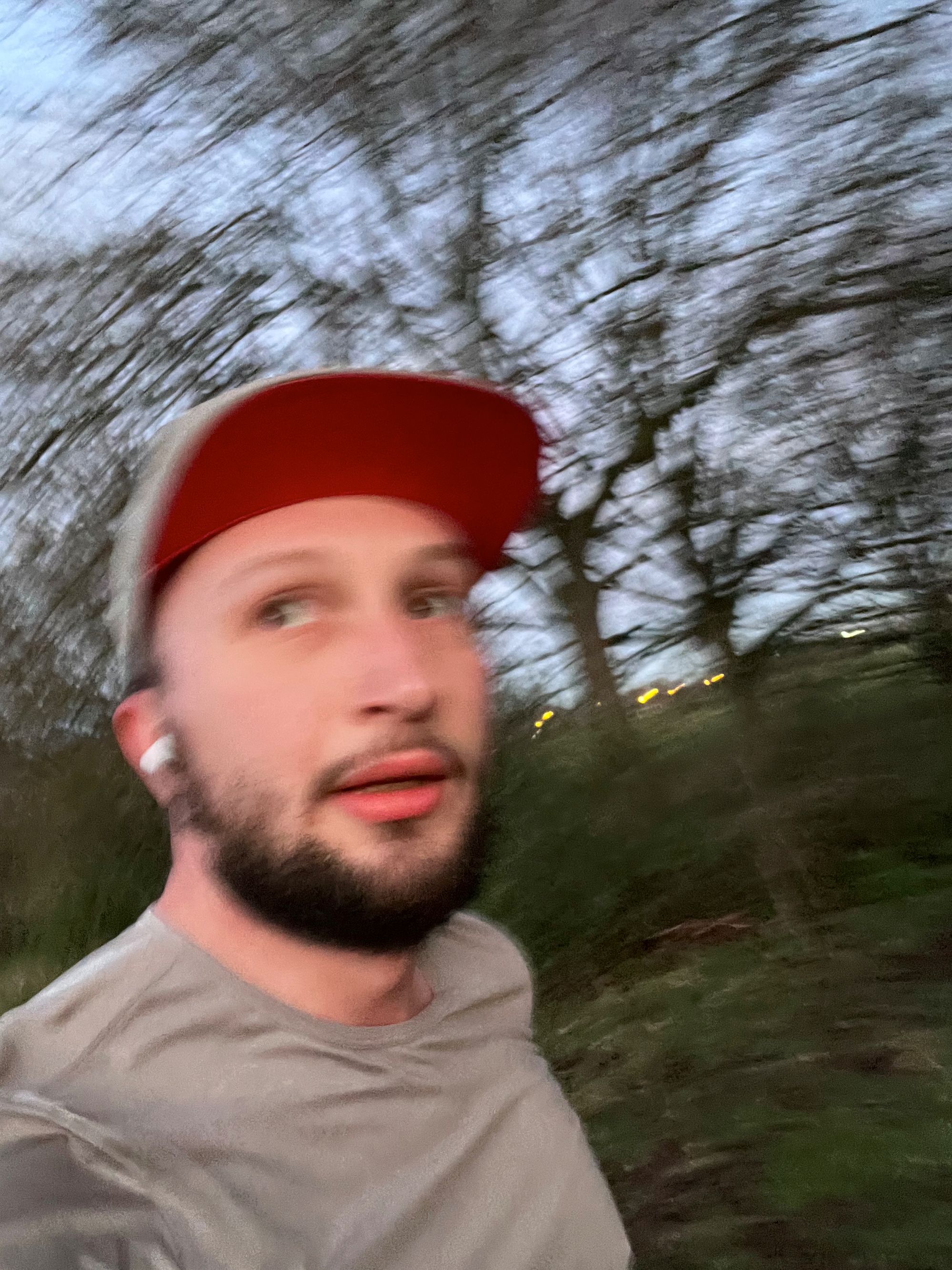 Jonathan running wearing a cap and a grey t-shirt, dusky, looking in the middle distance past the camera