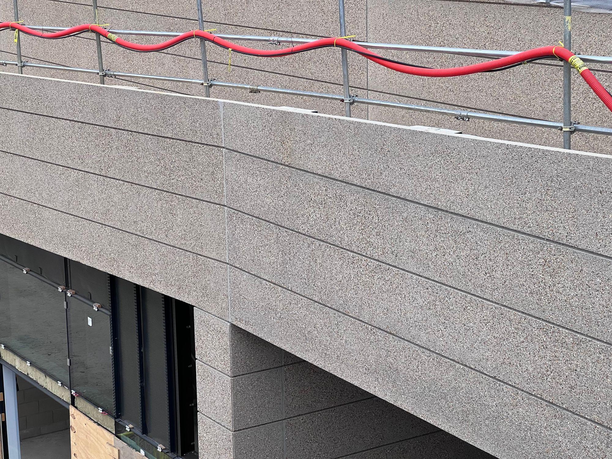 Close-up on some of the concrete cladding, which appears to be a thin layer with visible and messy joins between panels.