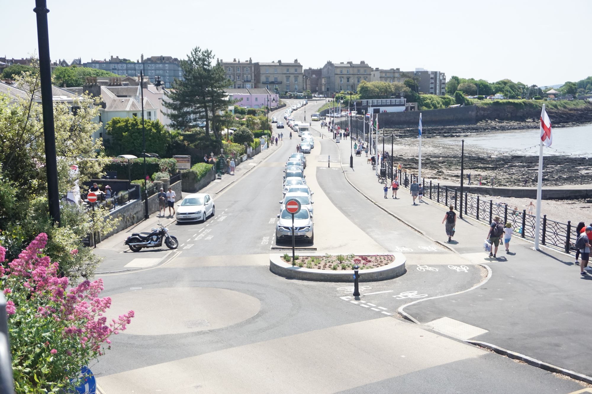 A buff-coloured circular 'roundabout' with a one-way road, a two-way cycle track with buff crossings, and a seaside with a shingle beach off to the right.