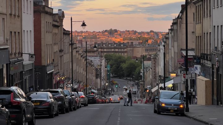 Looking down Park Street in Bristol at dusk. In the distance, the city is lit in golden light.