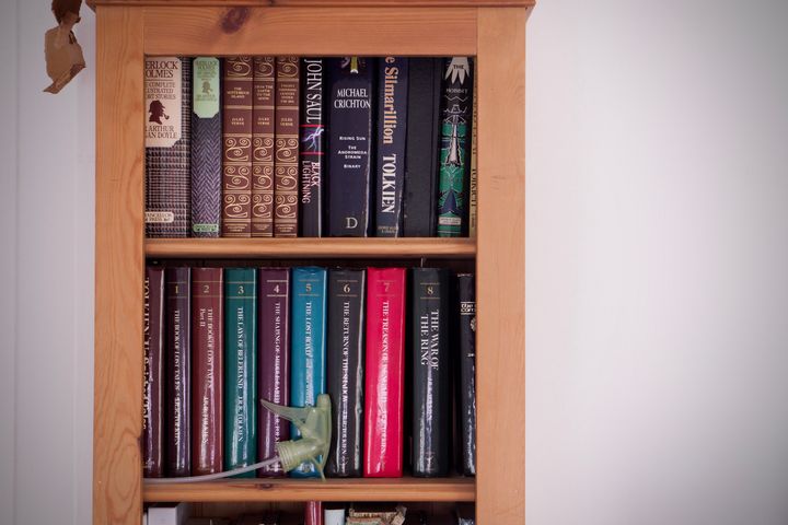 A bookshelf with a Sherlock Holmes, John Saul, Michael Crichton, Jules Verne, and a variety of Tolkien literature on it.