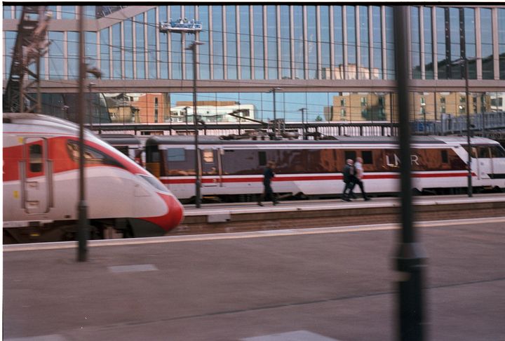 Two LNER trains at platforms as seen from a moving train. It's a scan of some film with visible dust spots & borders